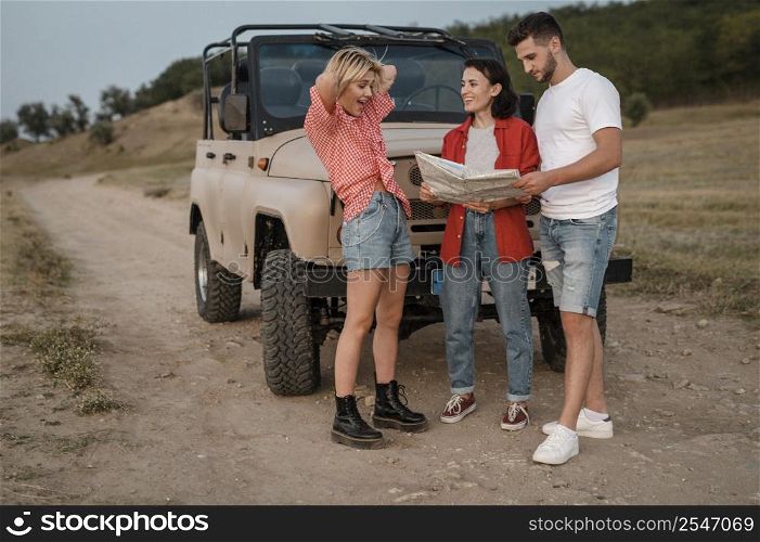 three good friends checking map while traveling by car