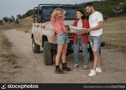 three good friends checking map while traveling by car