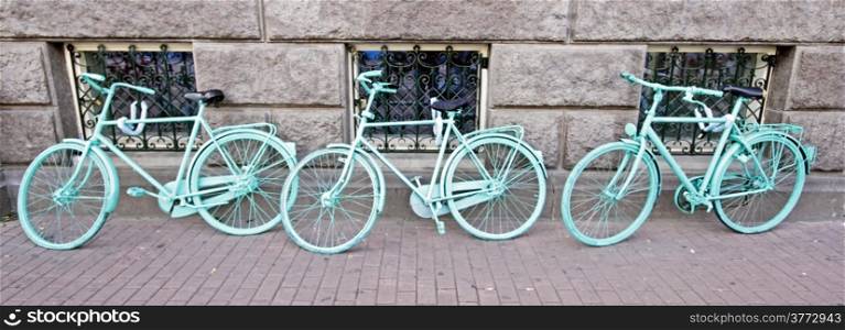 Three green bicycles against a wall in Amsterdam Netherlands