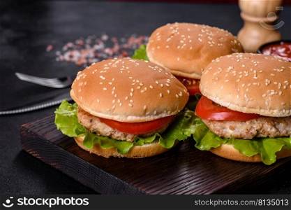 Three hamburger with beef meat burger and fresh vegetables on dark background. Tasty food. Three hamburger with beef meat burger and fresh vegetables on dark background