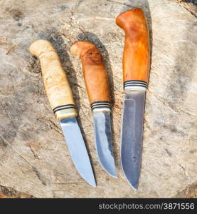 three hand made knives on tree stump