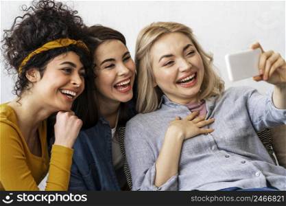three happy women smiling taking selfie