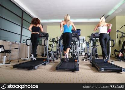 three healthy girls running on threadmill in fitness club