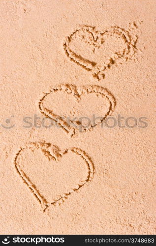 three hearts drawn on wet sand