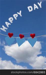 Three hearts with clothes pegs and three hearts of paper on a cord and text happy day