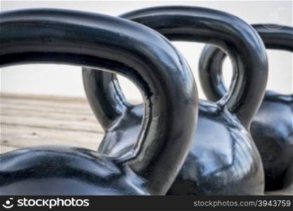 three heavy iron kettlebels on a wooden deck - fitness concept