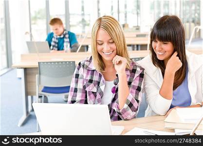 Three high school students in classroom with laptop studying