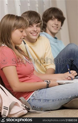 Three high school students sitting in a corridor