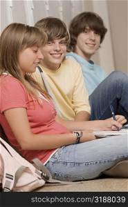 Three high school students sitting in a corridor