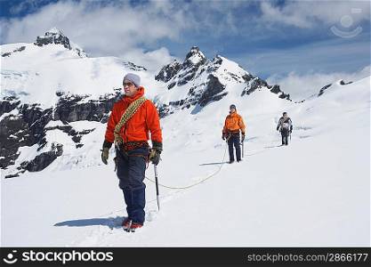 Three hikers joined by safety line in snowy mountains