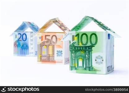 Three houses made of bank euro bills standing in a row isolated on white background