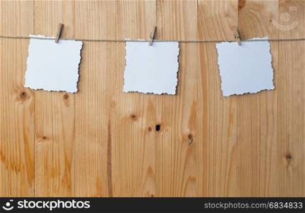 Three jagged note with clothes pegs on a cord on wood