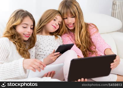 three kid sister friends girls group playing together with tablet pc on white sofa