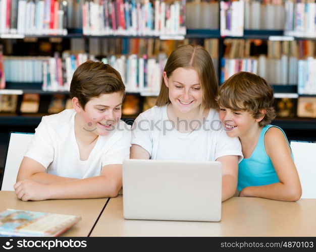 Three kids in library with notebook. Three kids in library