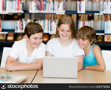Three kids in library with notebook. Three kids in library