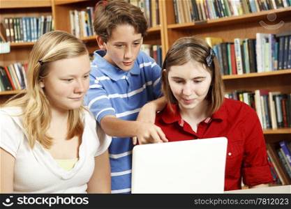 Three kids on the computer in the school library.