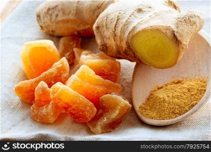 Three kinds of ginger - ground spice fresh and candied on rustic table. Healthy eating, home remedy for nausea upset stomach colds.