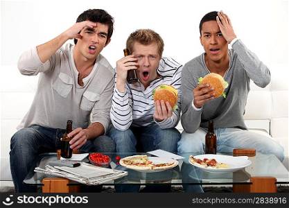 Three lads cringing at the television