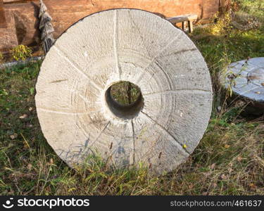 Three large millstones lying on the grass taken close-up.