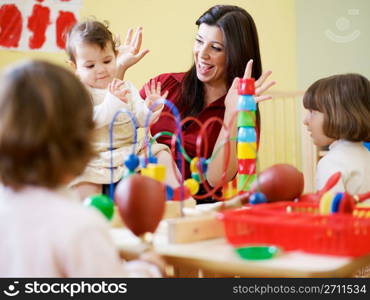 three little girls and female teacher in kindergarten