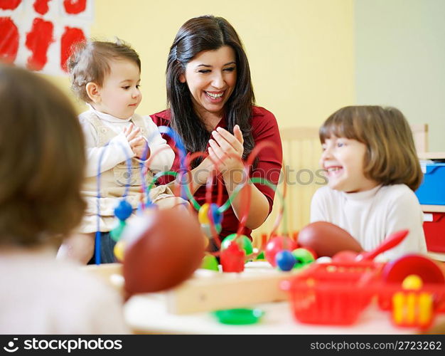 three little girls and female teacher in kindergarten