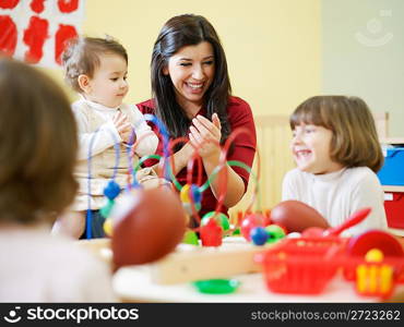 three little girls and female teacher in kindergarten