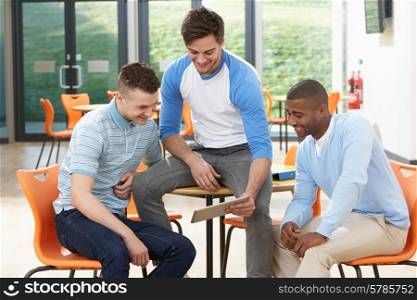 Three Male Students Looking At Digital Tablet In Classroom