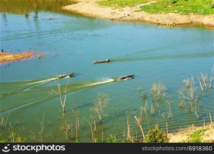 Three man moving fast forward on motor boat as boat race, boat make wave pattern on surface water at Nam ka lake, Dak lak, Viet Nam