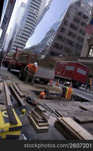 Three manual workers repairing a road