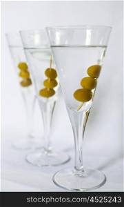 Three martini cocktails with olives against a white backdrop