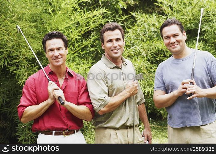 Three mature men holding golf clubs and smiling