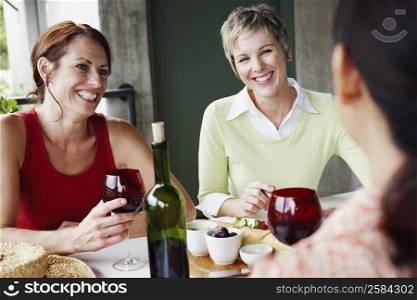 Three mature women sitting at the table and smiling