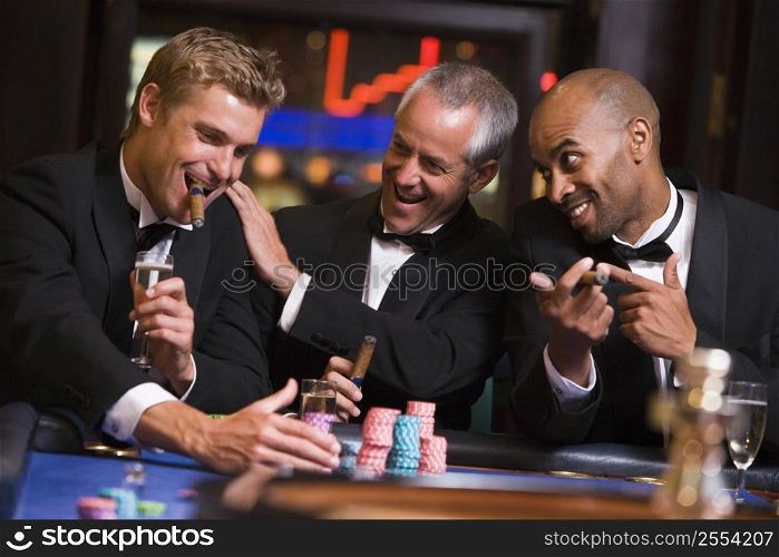Three men in casino playing roulette and smiling (selective focus)