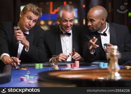 Three men in casino playing roulette and smiling (selective focus)