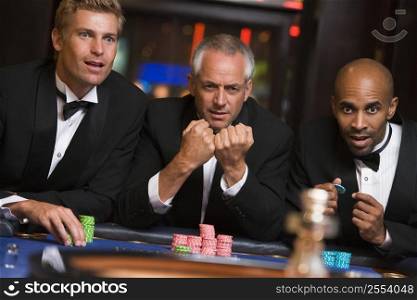 Three men in casino playing roulette (selective focus)
