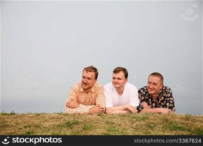 three men, laying on the grass