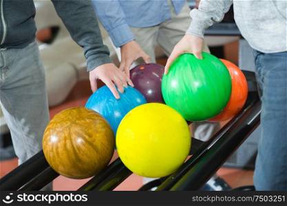 Three men selecting bowling balls