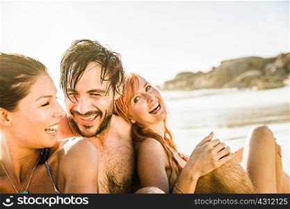 Three mid adult friends sitting together on beach, Cape Town, South Africa