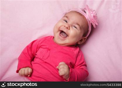 Three month old laughing baby girl in pink dress