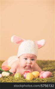 Three months baby lying on his stomach as a Easter bunny on the grass with eggs. Baby Easter bunny