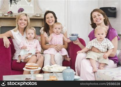 Three mothers in living room with babies and coffee smiling