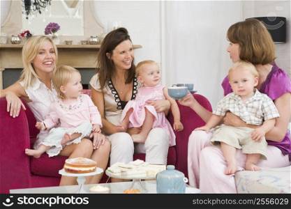 Three mothers in living room with babies and coffee smiling