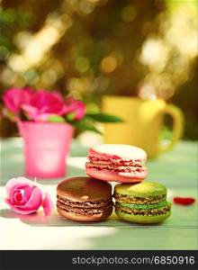 Three multi-colored almond macaroons on a white table, vintage toning