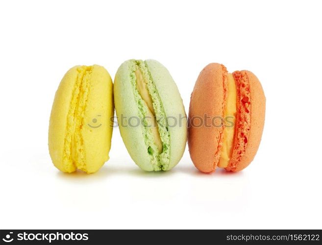 three multi-colored round baked macarons cakes isolated on a white background, dessert stands in a row