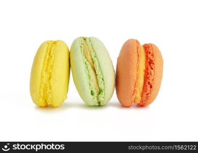 three multi-colored round baked macarons cakes isolated on a white background, dessert stands in a row