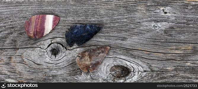 Three North America native American flint arrowheads on rustic wood surface for a vintage concept