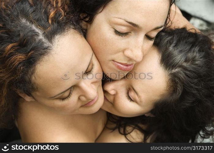 Three nude brunette Caucasian mid-adult women embracing each other with eyes closed.