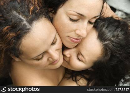 Three nude brunette Caucasian mid-adult women embracing each other with eyes closed.
