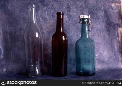 Three old empty bottles on painted background