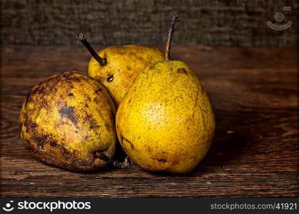 Three old pears on a wooden table background sacking